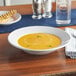 An Acopa bright white stoneware bowl of soup on a table.