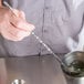 A person using a Tablecraft bar mixing spoon in a metal bowl with ice.