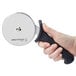 A hand holding a Dexter-Russell pizza cutter with a black handle.