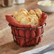 A bronze wire basket filled with bread on a table.