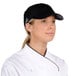A woman in a white uniform wearing a black Headsweats 5-panel cap.
