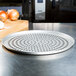 An American Metalcraft super perforated pizza pan on a counter next to onions.