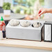 A person using a Steril-Sil countertop flatware organizer to hold utensils.