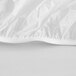 A close up of a white plastic tablecloth with elastic edges and a crease.