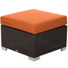 A brown wicker ottoman with a rust canvas cushion.