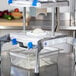 A Prince Castle Saber King slicer blade and pusher head assembly on a machine with a container of food.