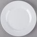 A white Minski melamine plate with a textured rim on a gray surface.