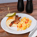 A Minski white melamine plate with a sandwich and macaroni and cheese on it.