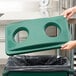 A woman using a green Rubbermaid Slim Jim recycling bin with a green lid.