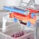 A Prince Castle Saber King 1/4" dicer blade and pusher head assembly in a machine with a container of chopped onions.