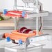 A Prince Castle Saber King 1/4" dicer blade and pusher head assembly on a table in a professional kitchen with a red onion in it.