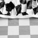 A black and white checkered round plastic tablecloth with elastic edges.