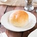 A Tuxton ivory china plate with scalloped edges holding a round of white bread.