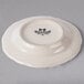 A Tuxton ivory china plate with scalloped edges and black text that says "Tuxton"