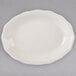 A white Tuxton oval china platter with a scalloped edge on a gray surface.