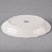 A white Tuxton oval china platter with a scalloped edge.