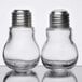 A close-up of American Metalcraft glass lightbulb salt and pepper shakers with silver tops.