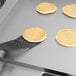 A pancake being flipped with a spatula on a Cooking Performance Group black pancake griddle.