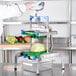 A person in a white coat using a Prince Castle Saber King lettuce chopper with a green and blue handle.
