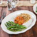 A Tuxton oval china platter with food on a table