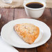 A Tuxton ivory china plate with a pastry on it next to a cup of coffee.