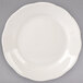 A Tuxton ivory china plate with scalloped edges on a gray background.