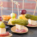 Tablecraft bamboo round dishes with meat, cheese, and pickles on wooden sticks.