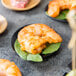 A Tablecraft black bamboo round dish holding shrimp on a table.