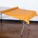 A table with a yellow plastic tablecloth on it.