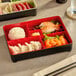 A black and red Bento Box tray with food in it.