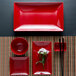 A red square Elite Global Solutions melamine plate with a white border and a flower on it.