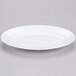 A white Elite Global Solutions oval melamine plate with a rim.