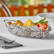 A Clipper Mill stainless steel boat basket of food on a table.