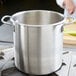 A Vollrath stainless steel stock pot on a stove.