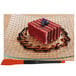 A piece of red velvet cake on a plate with blueberries on top and a Mercer Culinary silicone brush on the table.