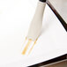 A white rectangular object with a black handle used to brush brown liquid on a white plate.