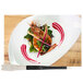 A white plate with a shrimp and red sauce next to a Mercer Culinary round arch silicone brush.