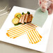 A person using a Mercer Culinary silicone wedge plating tool to arrange food on a plate.