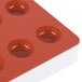 A red silicone round tray with 24 fruit jelly compartments.