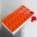 A red silicone round tray with 24 fruit-shaped compartments.