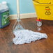 A Rubbermaid Web Foot wet mop on a wooden floor.