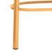 The gold metal leg of a Lancaster Table & Seating chair with a wood grain leg glide.