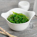 A Libbey Royal Rideau white porcelain bowl of seaweed with chopsticks.