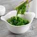 A bowl of seaweed with chopsticks in a Libbey Royal Rideau white porcelain handle bowl.