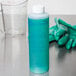 A blue bottle of Manitowoc ice machine cleaner next to gloves.