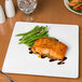 A Libbey white porcelain plate with a piece of salmon and green beans on it.