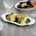 A white Libbey porcelain platter with food and a glass of wine on a table.