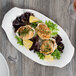 A close up of Libbey white porcelain platter with food on a table.