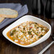 A bowl of Libbey Royal Rideau white porcelain filled with soup, pasta, and vegetables.