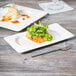 A Libbey white porcelain rectangular tray with food on a table.